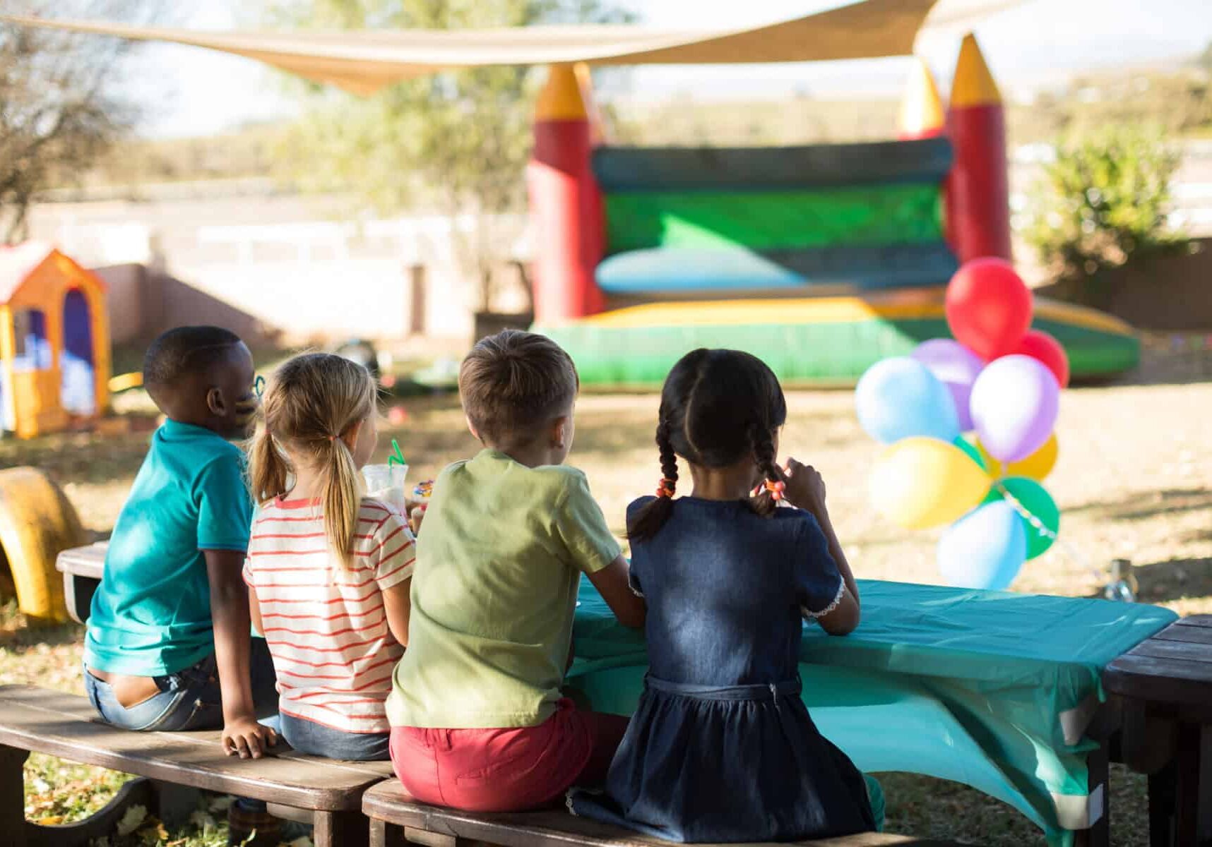 Rear view of children sitting on bench at park