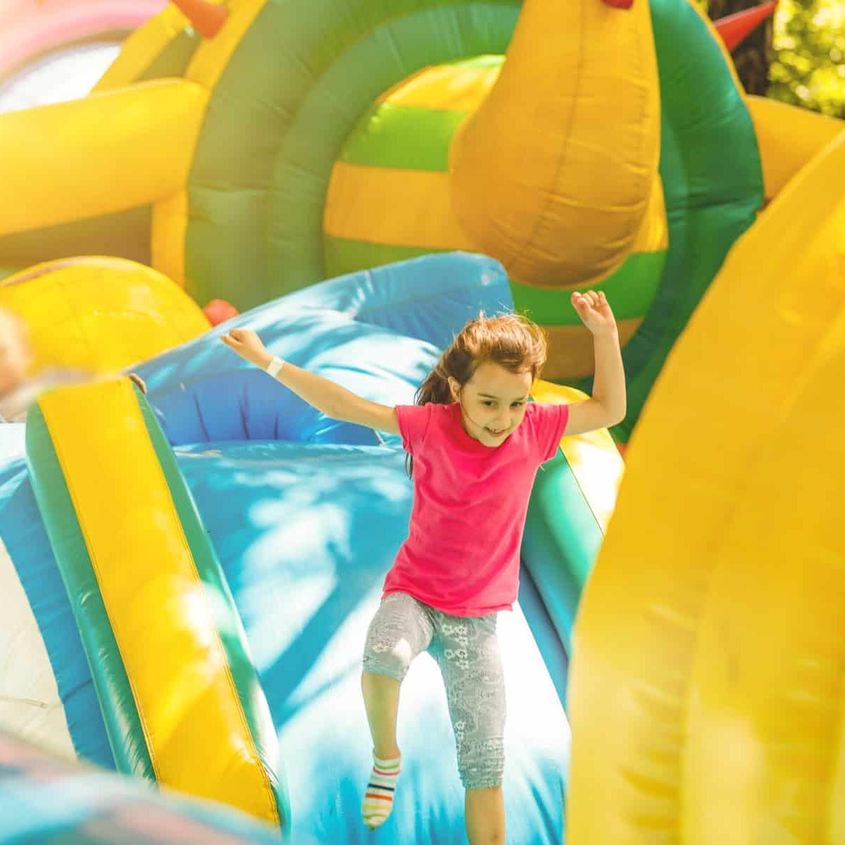 Happy little girl having lots of fun on a jumping castle during sliding