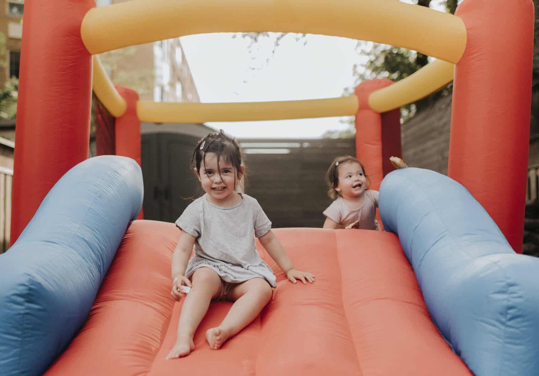 Sisters playing on inflatable slide
